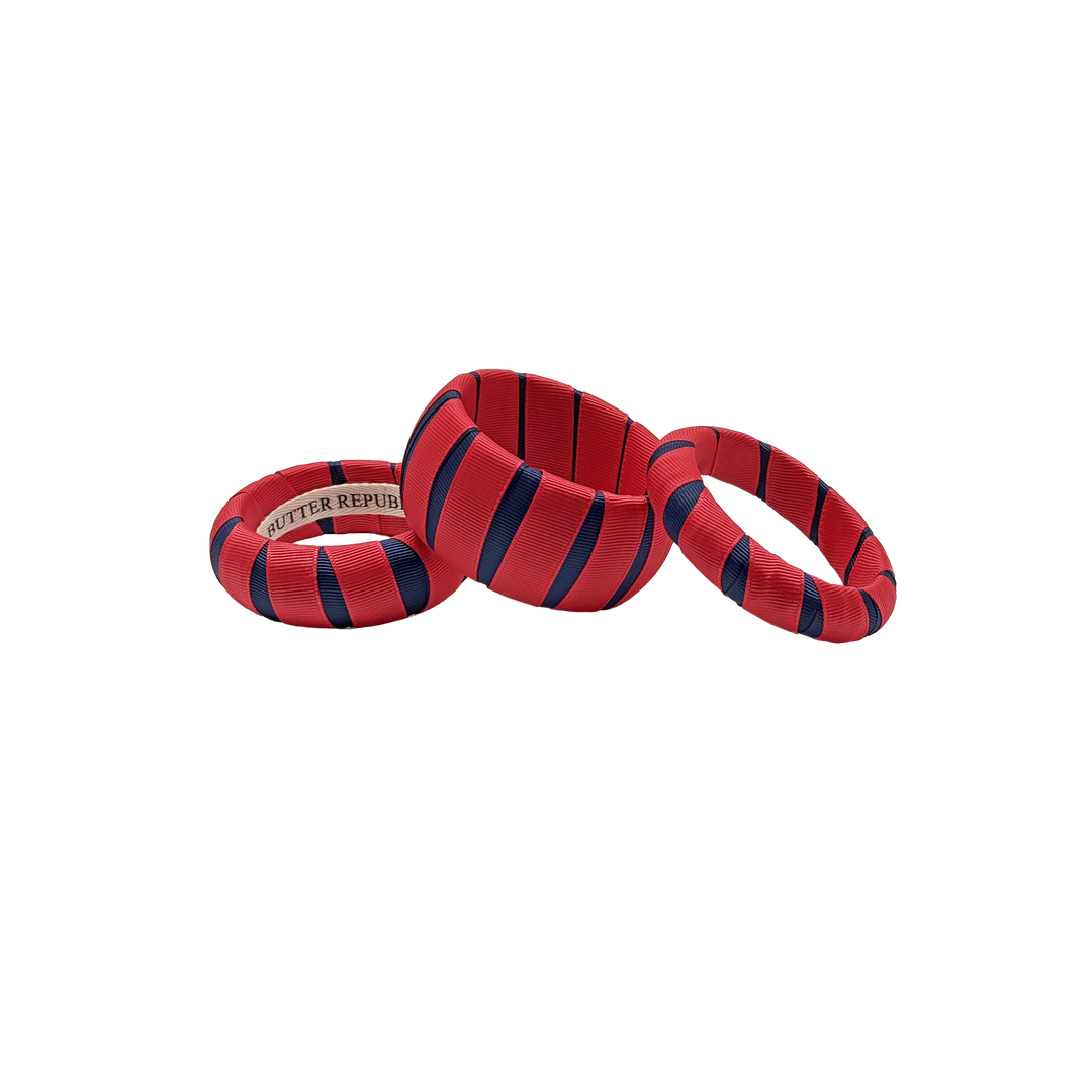 three multi-width red and navy blue Butter Republic bracelets with logo brand label on the interior of the bracelet