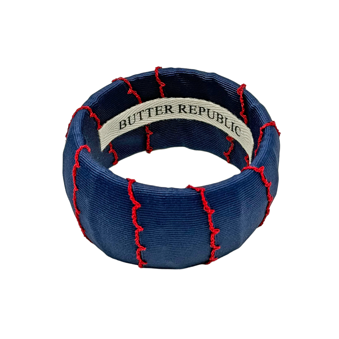 A wide navy blue Butter Republic bracelet with red trim accent; brand label affixed to the interior