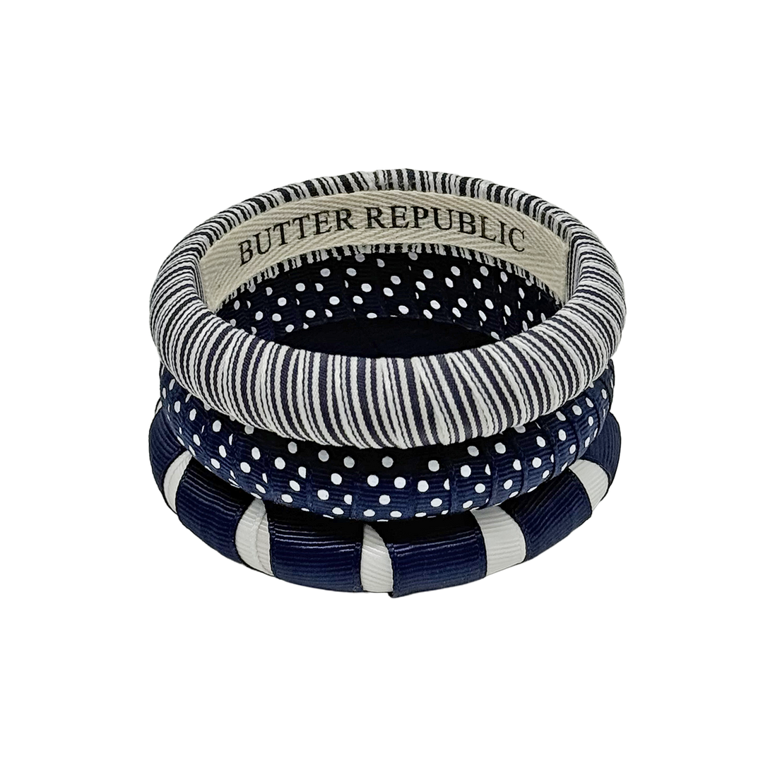 A stack of three assorted patterns of navy blue and white Butter Republic bracelets
