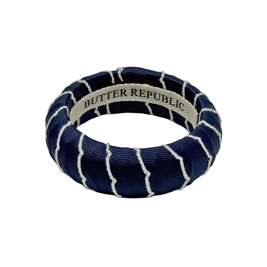 navy blue and white moonstitch Butter Republic bracelet with logo brand label on an interior of the bracelet