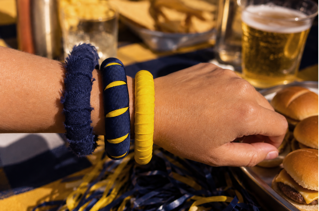 A close-up of a woman's wrist wearing navy blue and yellow Butter Republic bangle bracelets