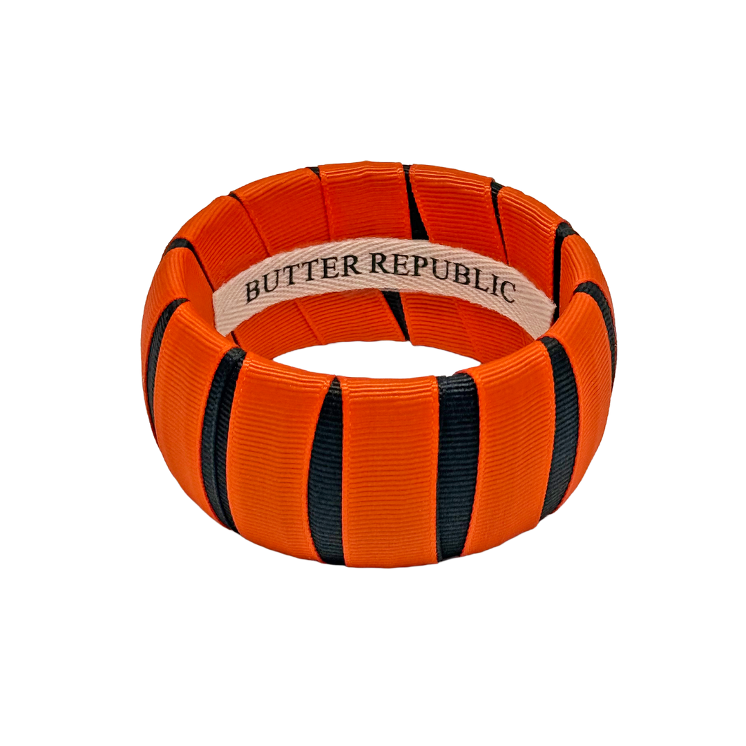 An orange and black Butter Republic ribbon-wrapped bangle bracelet