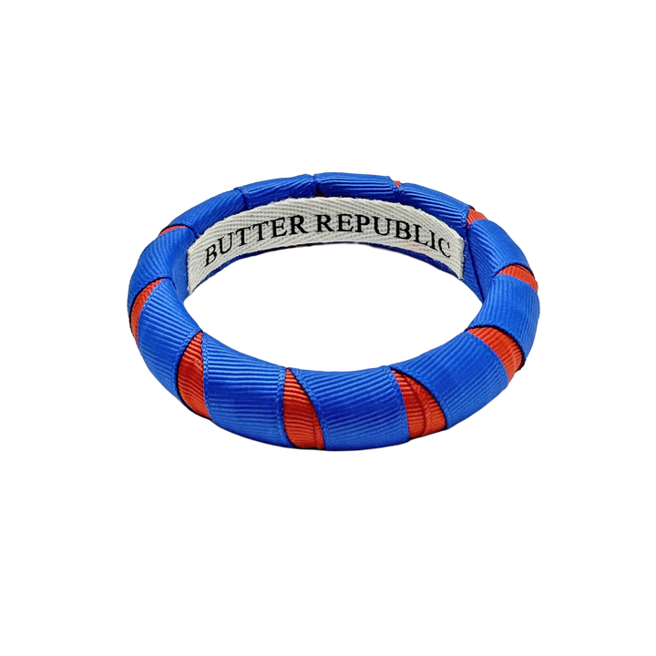 orange and blue Butter Republic bracelet with logo brand label on the interior of the bracelet
