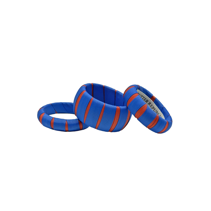 three multi-width orange and blue Butter Republic bracelets with logo brand label on the interior of the bracelet