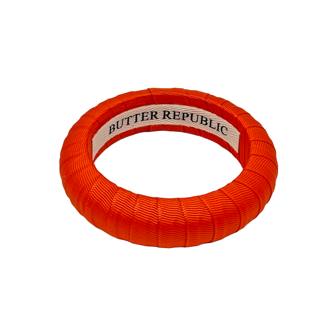 Orange bracelet with Butter Republic brand label on a white background