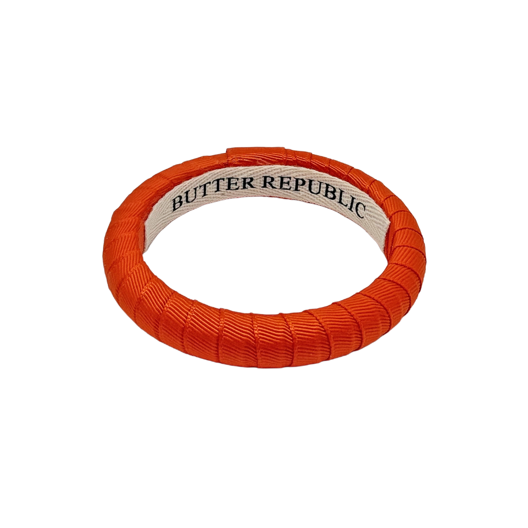 narrow orange Butter Republic bracelet with brand label on the interior