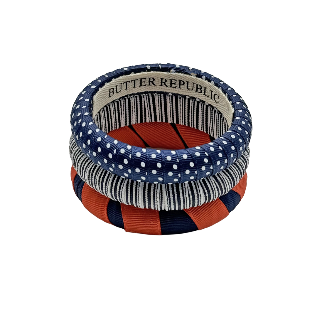 Three orange and navy blue bracelets with visible 'Butter Republic' brand name on a white background