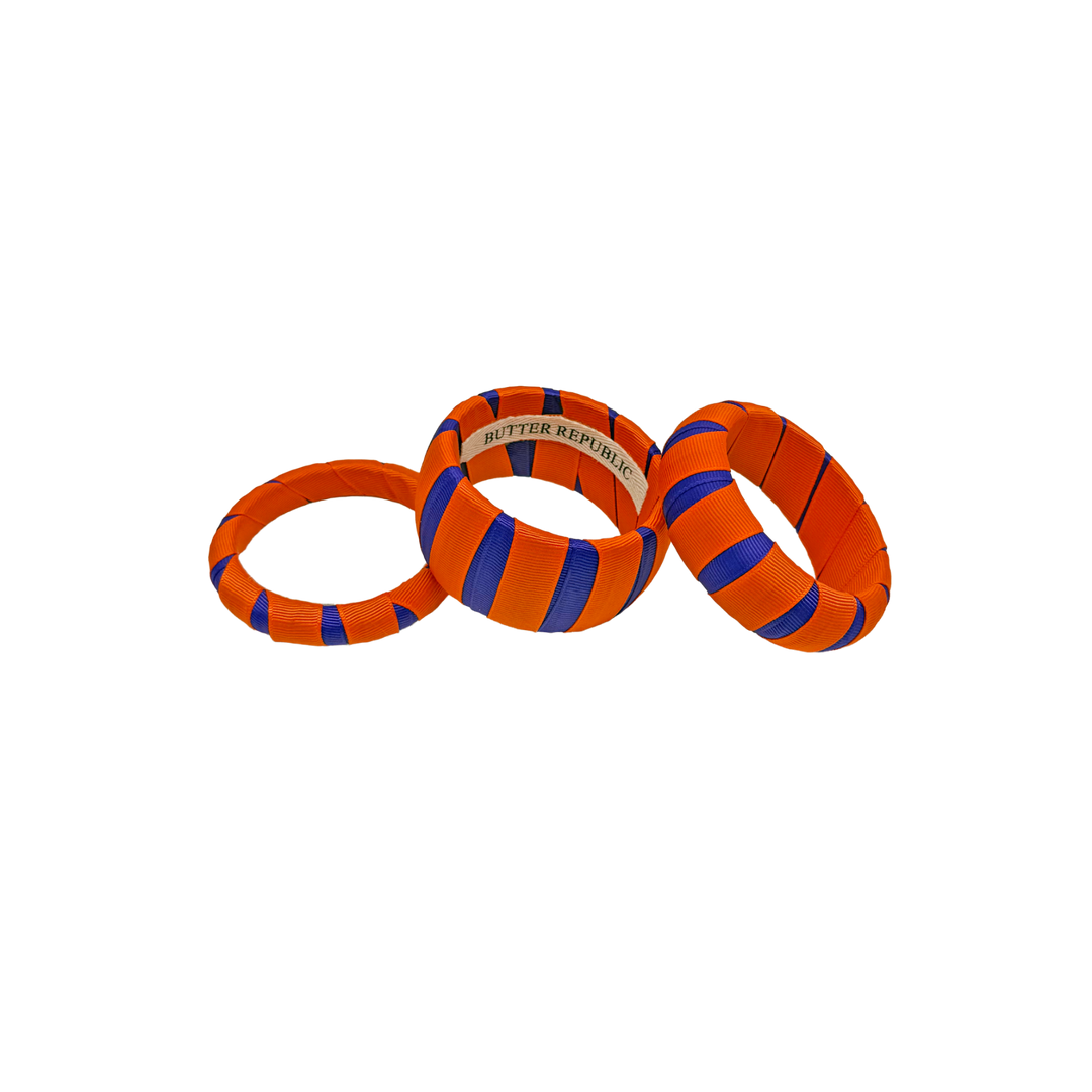 Three orange and purple Butter Republic bracelets with brand label on the interior