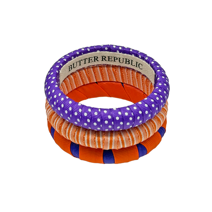 Stack of purple and orange Butter Republic bangles with the brand name label on the interior