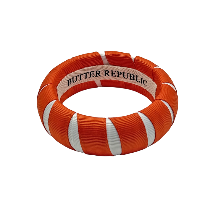 orange and white Butter Republic bracelet with logo brand on the interior of the bracelet