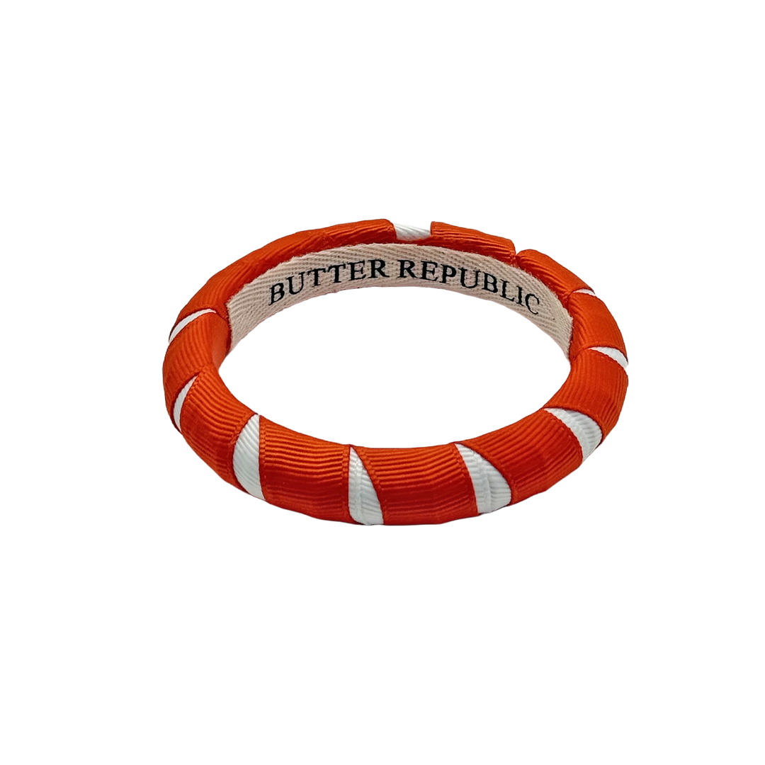 orange and white Butter Republic bracelet with logo brand label on the interior of the bracelet