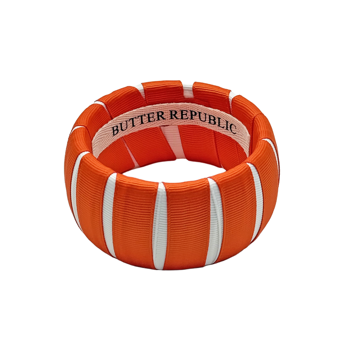 orange and white Butter Republic bracelet with logo brand label on the interior of the bracelet