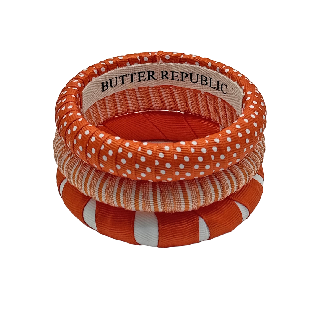 stack of three orange and white narrow Butter Republic bracelets with logo brand label on the interior of the bracelet