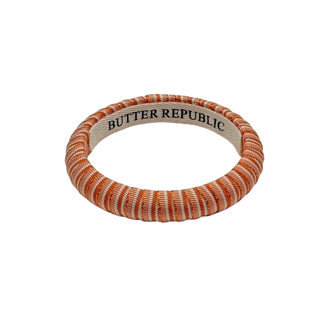 orange and white striped Butter Republic bracelet with logo brand label on the interior of the bracelet