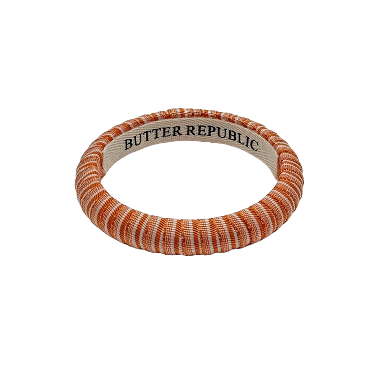 orange and white striped Butter Republic bracelet with logo brand label on the interior of the bracelet