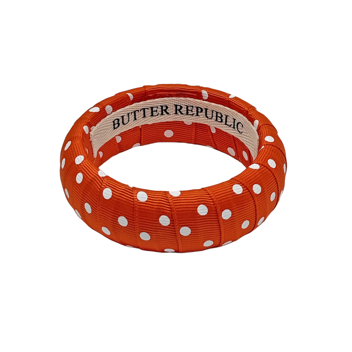 orange and white polka dot Butter Republic bracelet with a brand label on the interior of the bracelet