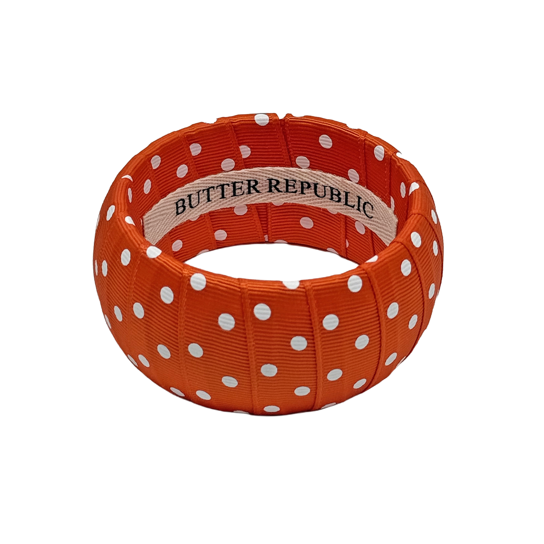 orange and white polka dot Butter Republic bracelet with a brand label on the interior of the bracelet