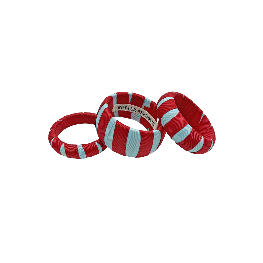 set of three different sized red and powder blue Butter Republic bracelets with a brand label on the interior of each bracelet