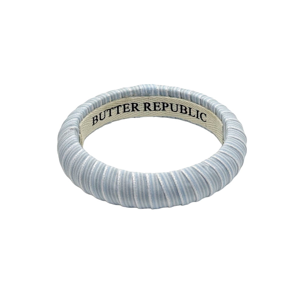 powder blue and white pinstripe Butter Republic bracelet with logo branding on the interior of the bracelet