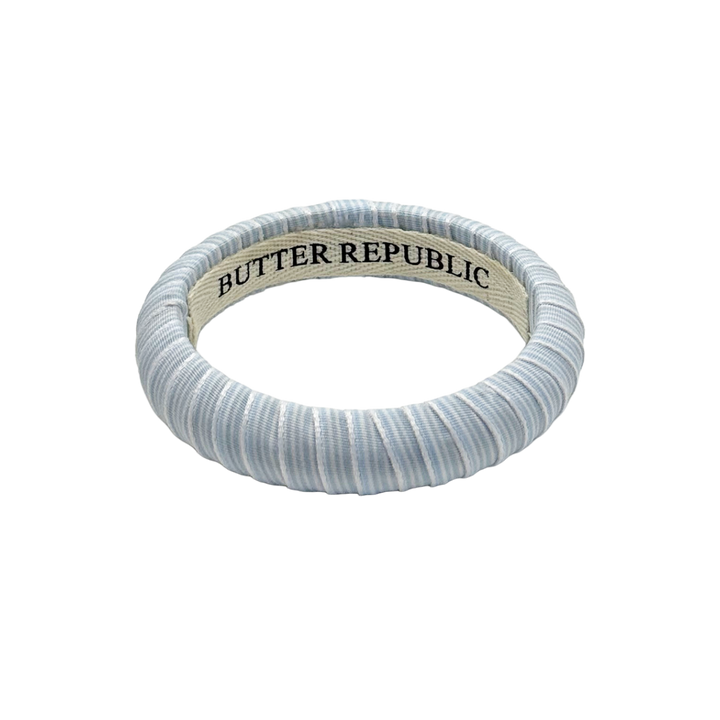 powder blue and white pinstripe Butter Republic bracelet with logo branding on the interior of the bracelet