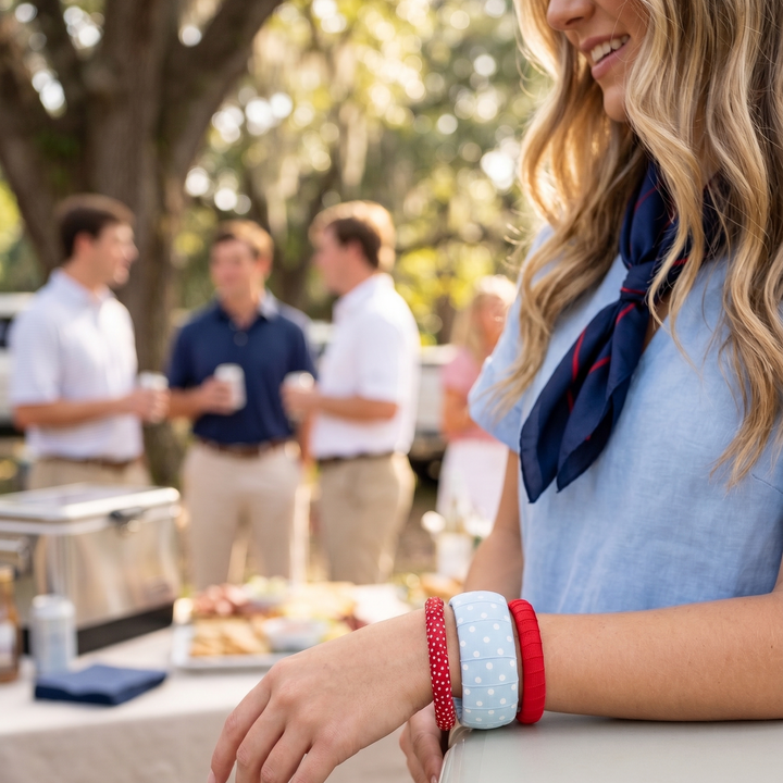 A young woman in a powder blue dress, wearing a Butter Republic stack of blue and red bracelets at a tailgate party