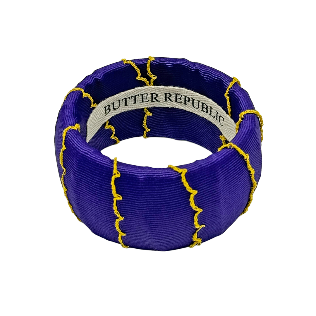 Purple bracelet with yellow accents and 'Butter Republic' branding on the interior