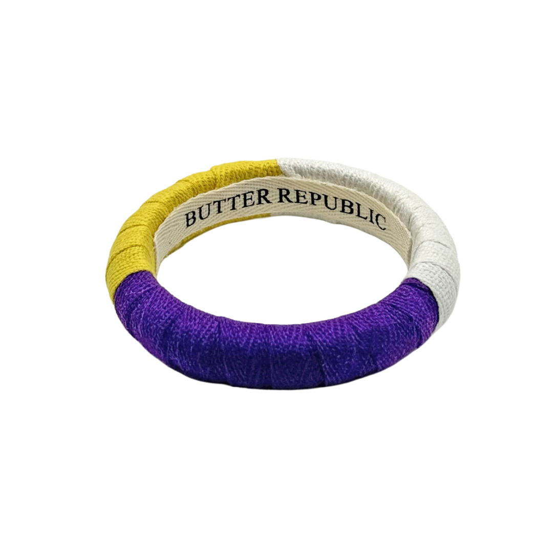 purple, yellow, and white color-block Butter Republic bracelet with a brand label on the interior of the bracelet