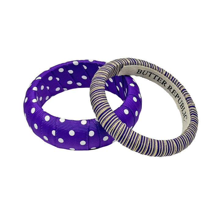 Two purple and white bracelets with Butter Republic brand labeling on the interior, one with polka dots and the other striped