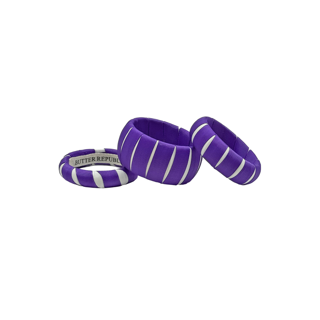 three multi-sized purple and white Butter Republic bracelets with a brand label on the interior of one of the bracelets