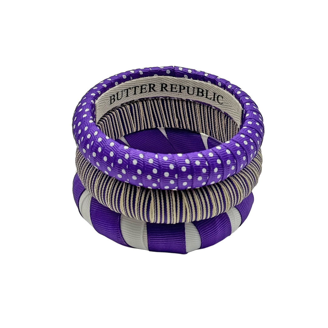 set of three purple and white Butter Republic bracelets with a brand label on the interior of one of the bracelets