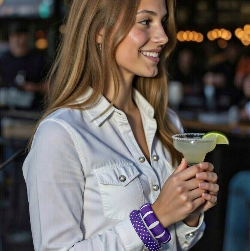woman wearing two purple and white Butter Republic bracelets while holding a margarita and wearing a lognsleeve white denim shirt with pearl buttons