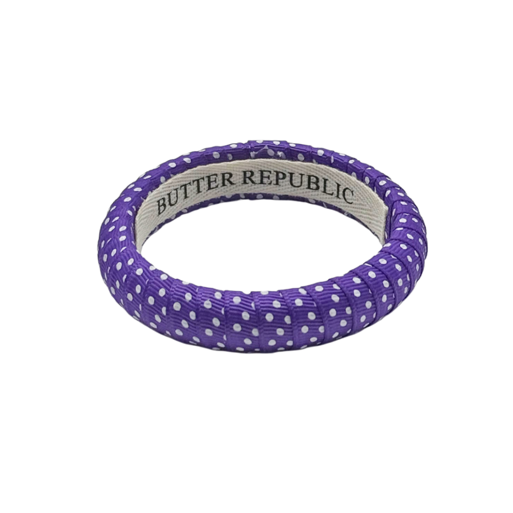 purple and white Swiss dot narrow Butter Republic bracelet with a brand label on the interior of the bracelet