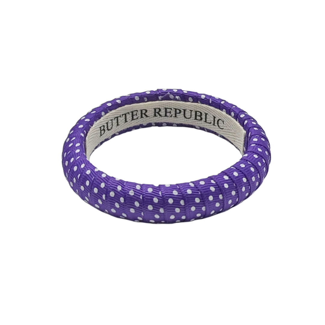 purple and white Swiss dot narrow Butter Republic bracelet with a brand label on the interior of the bracelet