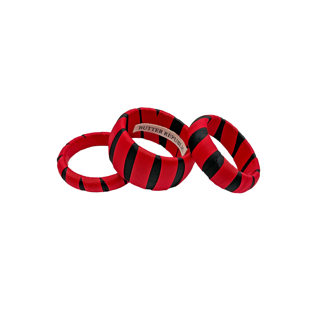 three multi-sized red and black Butter Republic bracelets with a brand label on the interior of one of the bracelets