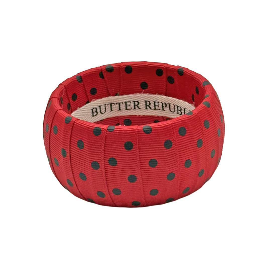 red bracelet with black polka dots with a Butter Republic brand label on the interior of the bracelet