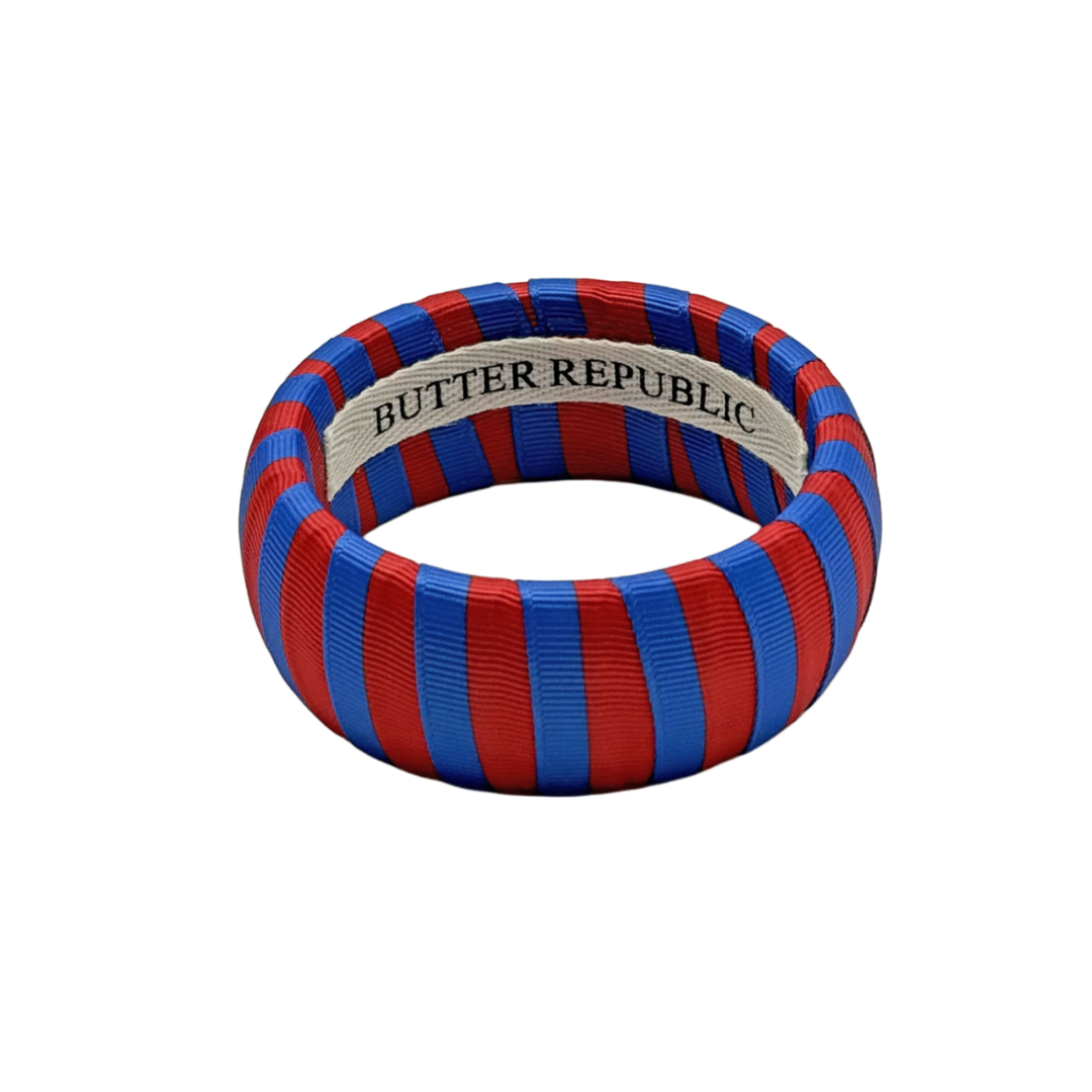red and blue striped Butter Republic bracelet with a logo brand label on the interior of the bracelet