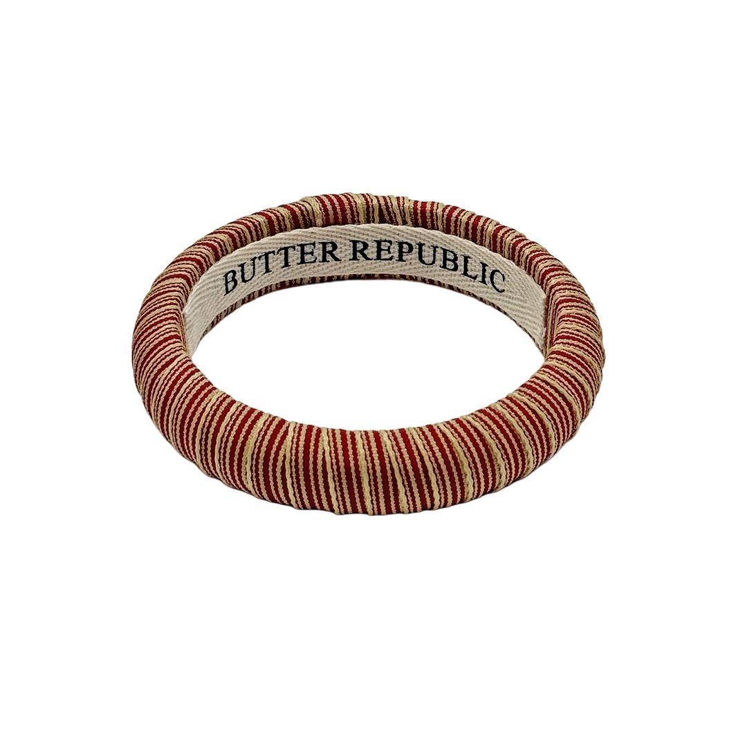 red and cream pinstripe Butter Republic bracelet with a logo brand label on the interior of the bracelet