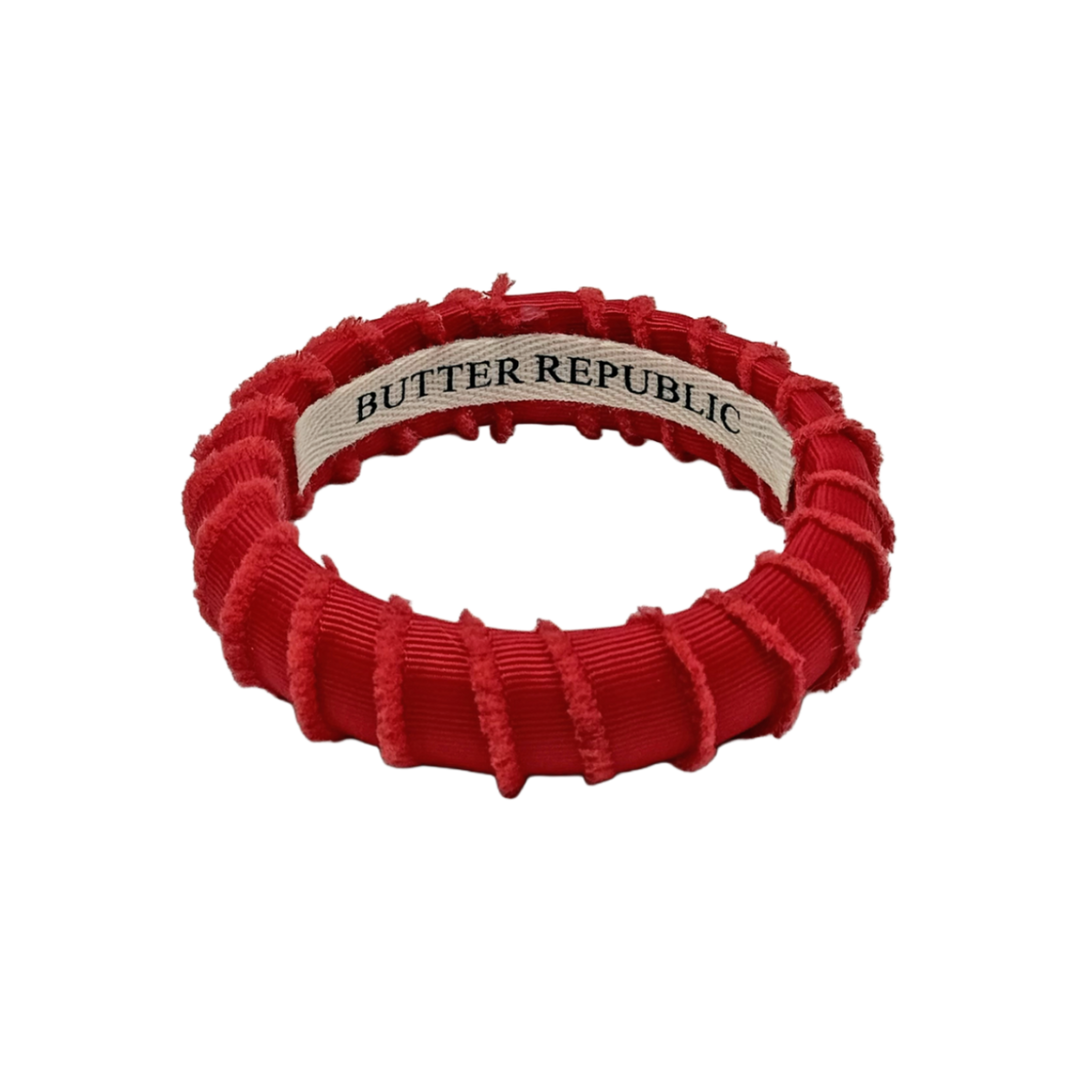 red frayed Butter Republic bracelet with a logo brand label on the interior of the bracelet