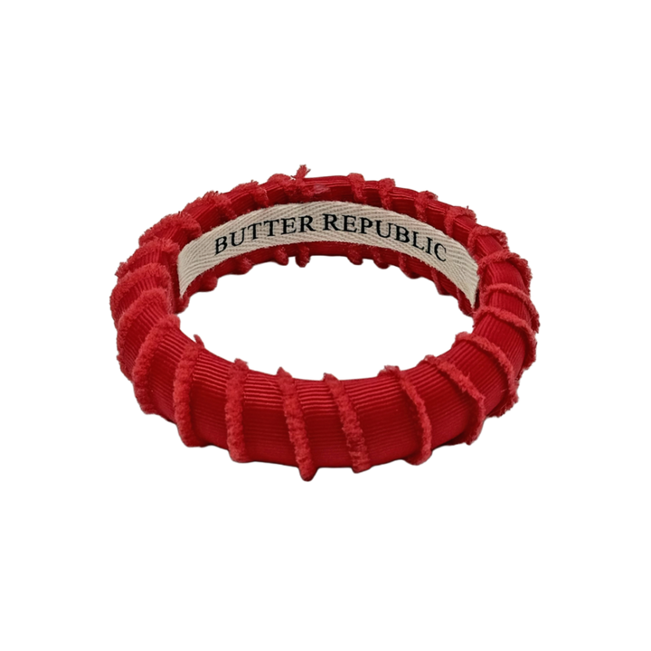 red frayed Butter Republic bracelet with a logo brand label on the interior of the bracelet