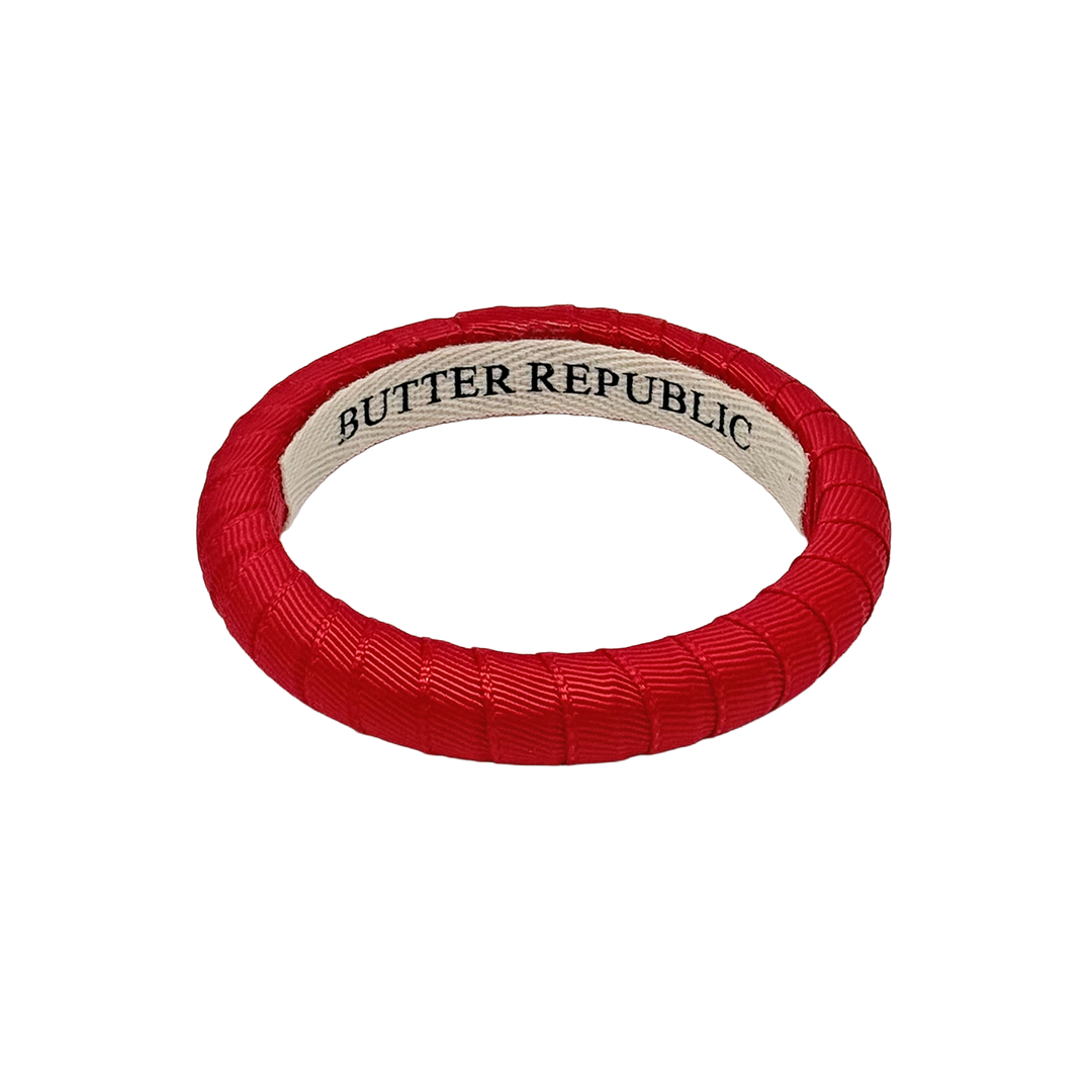 narrow red Butter Republic bracelet with a logo brand label on the interior of the bracelet