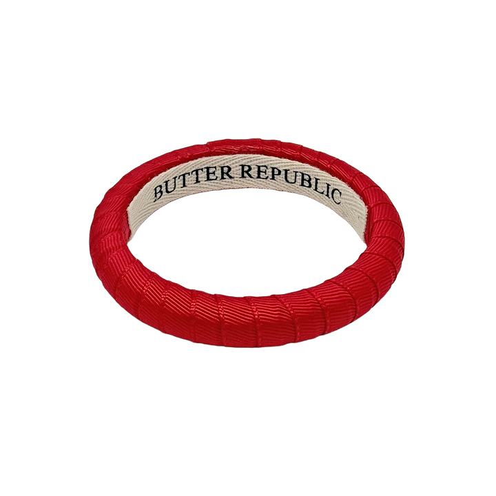 narrow red Butter Republic bracelet with a logo brand label on the interior of the bracelet