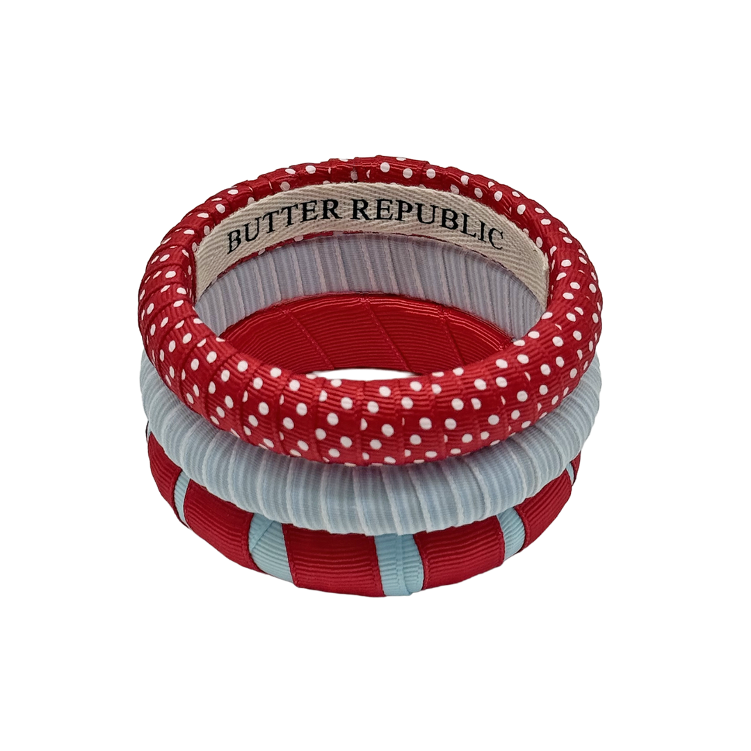 set of three powder blue and red Butter Republic bracelets with a logo brand label visible on the interior of one of the bracelets