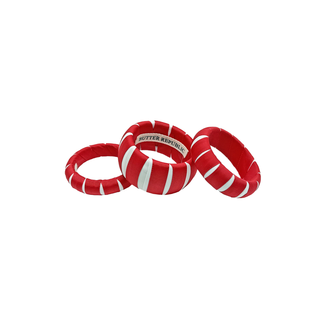 three multi-sized red and white Butter Republic bracelets with a logo brand label visible on the interior of one of the bracelets