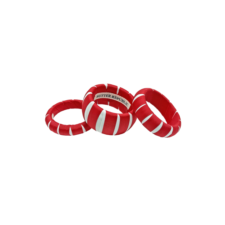 three multi-sized red and white Butter Republic bracelets with a logo brand label visible on the interior of one of the bracelets