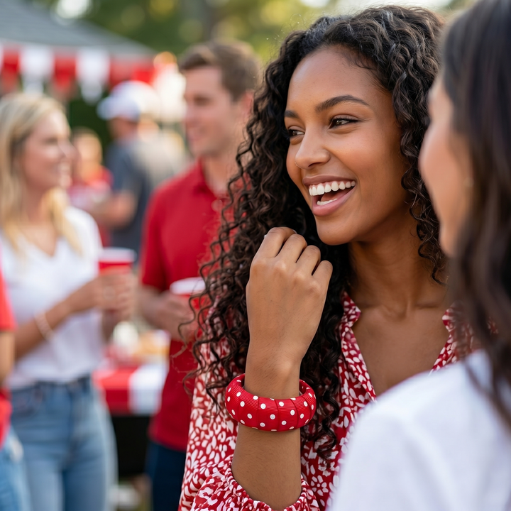 Woman wearing a red and white polka dot Butter Republic bangle bracelet at an outdoor event with people in the background.