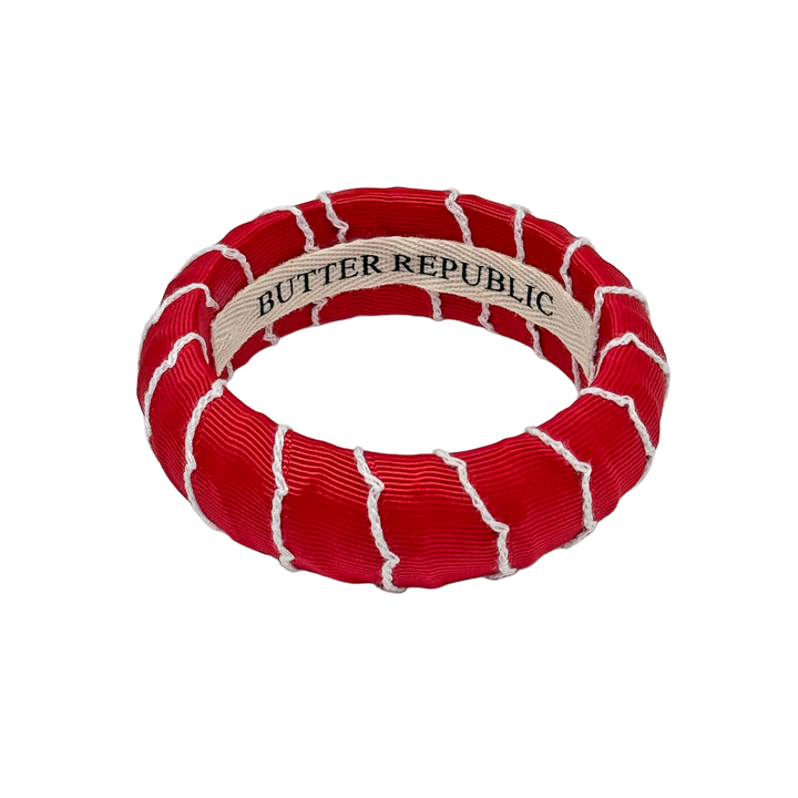 Red and white bracelet with Butter Republic branding label on the interior