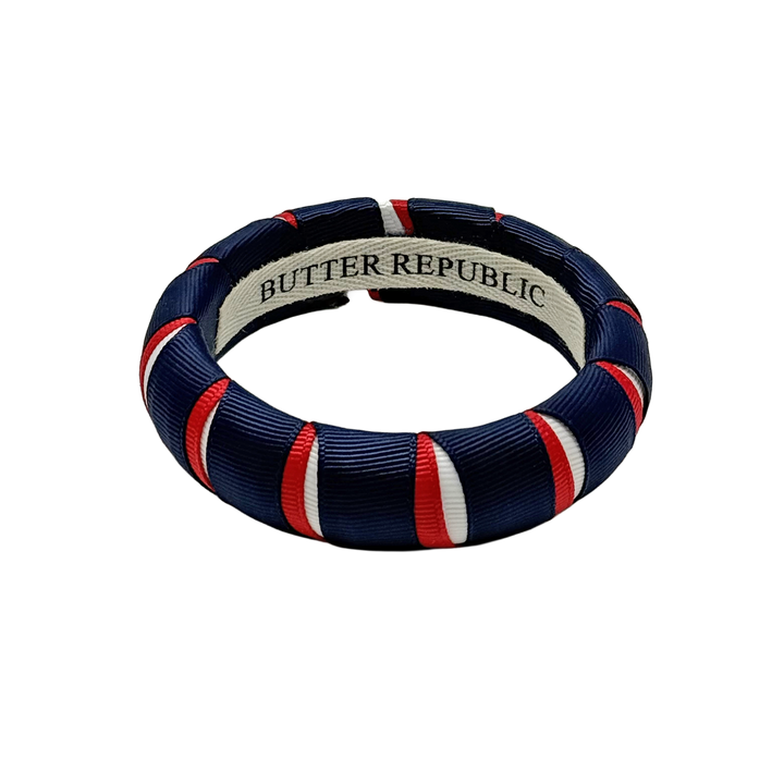 red, white, and navy blue Butter Republic bracelet with a logo brand label on the interior of the bracelet