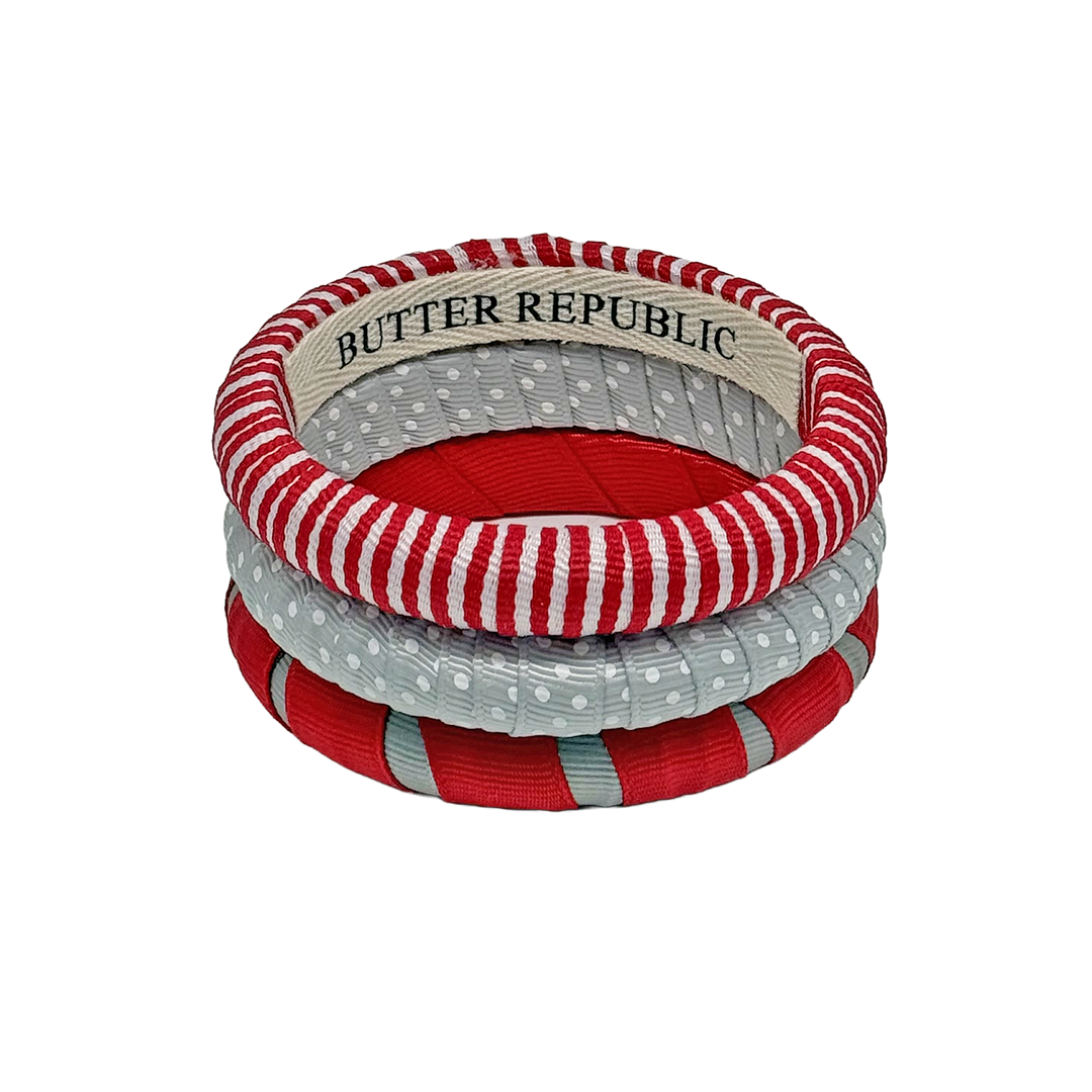 Three stacked red, gray, and white Butter Republic bangles