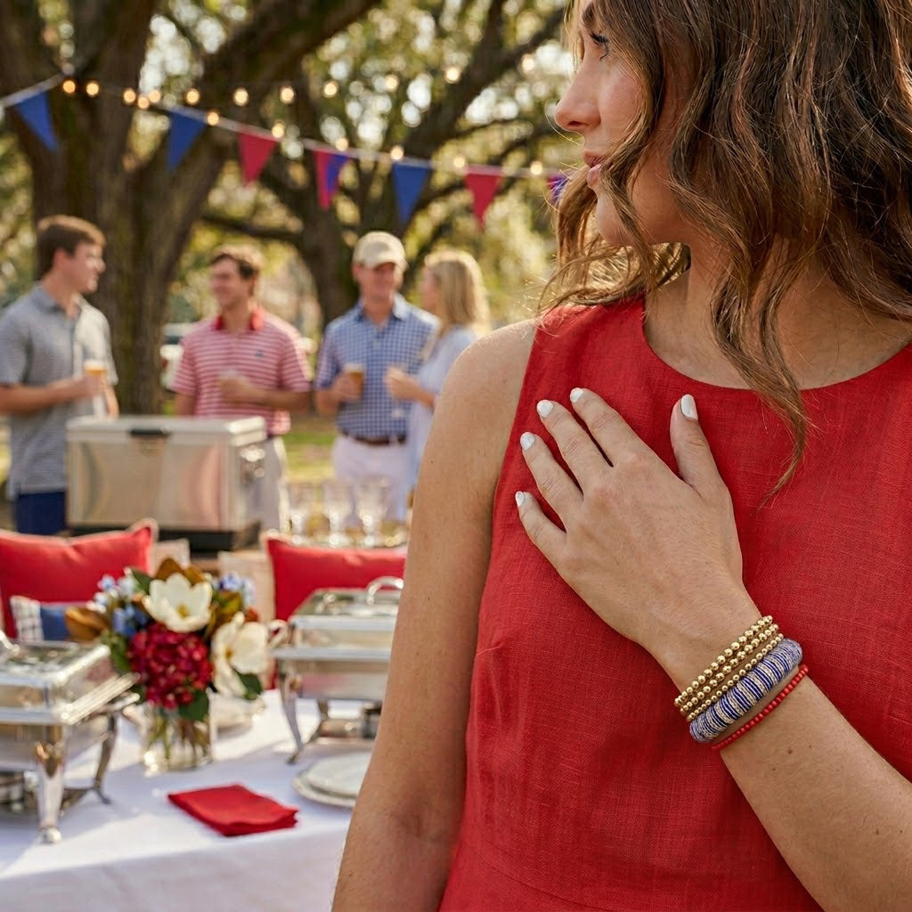young woman in a red dress wearing a navy blue and white striped Butter Republic bracelet at an outdoor event with people and tables
