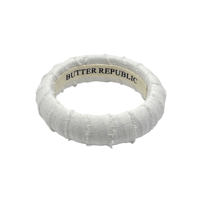 white frayed Butter Republic bracelet with logo brand label visible on the interior of the bracelet